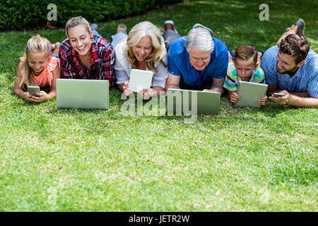 Glückliche Familie mit Technologien liegen in Hof Stockfoto