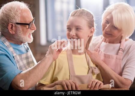 Großmutter, Großvater und Enkelin Kochen und Kneten von Teig für Kekse mit Küchenutensilien, Kochen in der Küche concept Stockfoto