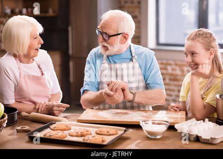 Großmutter, Großvater und Enkelin Kochen und Kneten von Teig für Kekse am Küchentisch, Kochen in der Küche concept Stockfoto