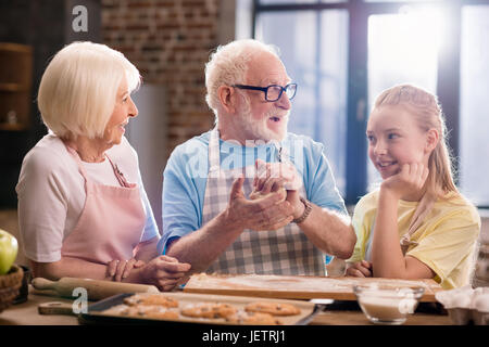 Großmutter, Großvater und Enkelin Kochen und Kneten von Teig für Kekse am Küchentisch, Kochen in der Küche concept Stockfoto