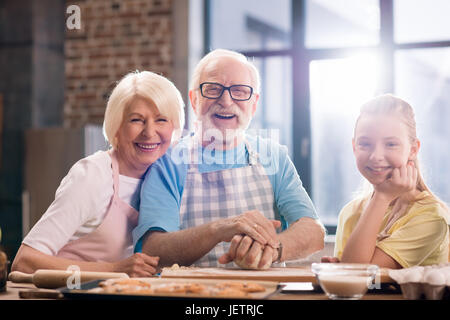 Großmutter, Großvater und Enkelin Kochen und Kneten von Teig für Kekse am Küchentisch, Kochen in der Küche concept Stockfoto