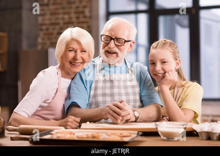 Großmutter, Großvater und Enkelin Kochen und Kneten von Teig für Kekse am Küchentisch, Kochen in der Küche concept Stockfoto