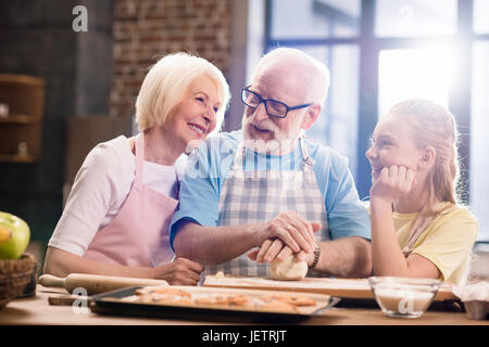 Großmutter, Großvater und Enkelin Kochen und Kneten von Teig für Kekse am Küchentisch, Kochen in der Küche concept Stockfoto