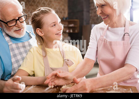 Großmutter, Großvater und Enkelin Kochen und Kneten von Teig für Kekse am Küchentisch, Kochen in der Küche concept Stockfoto