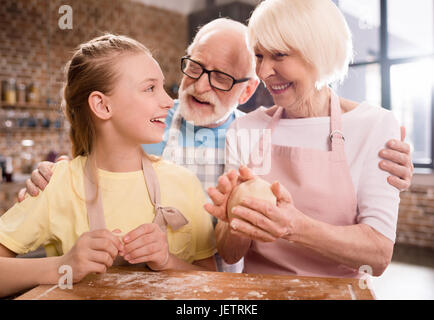Großmutter, Großvater und Enkelin Kochen und Kneten von Teig für Kekse am Küchentisch, Kochen in der Küche concept Stockfoto