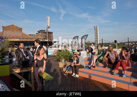 Menschen genießen Sie einen Drink an der Bar neben dem Pen-Air-Kino auf dem Dach des Gebäudes Bussey in Peckham, London, UK Stockfoto