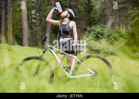 Frau Trinkwasser neben ihr Fahrrad Stockfoto