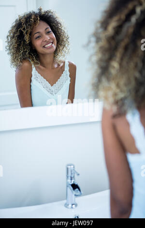 Frau, Blick in den Spiegel und Lächeln Stockfoto