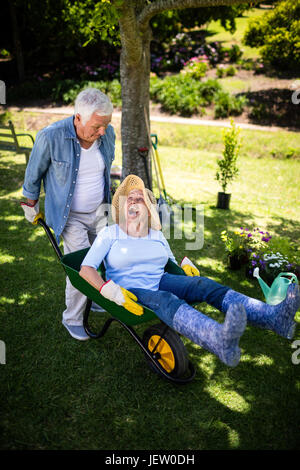 Älteres Paar spielen mit einer Schubkarre Stockfoto