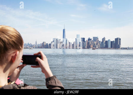 Junge Frau nehmen Foto von Manhattan mit ihrem smartphone Stockfoto