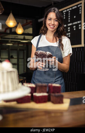 Lächelnde Barista Halteplatte mit Kuchen Stockfoto