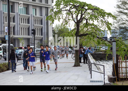 TOKYO, JAPAN - ca. April 2013: Japanische Jugendliche joggen durch die Innenstadt. Schuljungen, die Ausbildung ist auf städtischen Straßen. Stockfoto