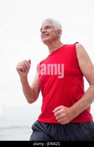 Senior woman jogging am Strand Stockfoto