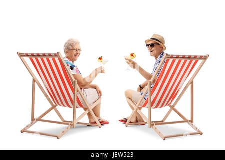 Ältere Touristen mit Cocktails sitzen in Liegestühlen und Blick auf die Kamera isoliert auf weißem Hintergrund Stockfoto