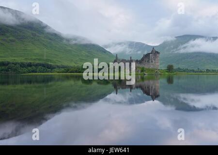 Reflexionen an einem bewölkten Morgen der Ruine des Kilchurn Castle. Das Bild wurde von den Ufern des Loch Awe an einem noch bewölkten Morgen aufgenommen. Stockfoto