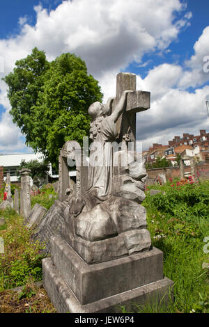 LONDON, ENGLAND - 12. Juli 2017 Grabsteine in Tower Hamlets Cemetery Park in London. Mädchen klammerte sich an das Kreuz Stockfoto