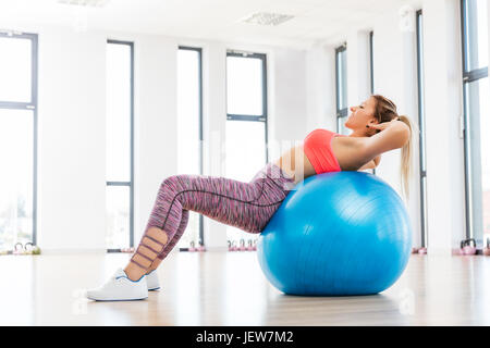Junge Frau mit Fitball im Fitnessclub trainieren. Fatburning und Körperformung Konzept. Stockfoto