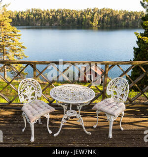 Metall-Stühle und Tisch auf der Terrasse mit Blick auf den See Stockfoto