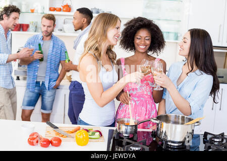 Freunde, toasten Weingläser in Küche Stockfoto