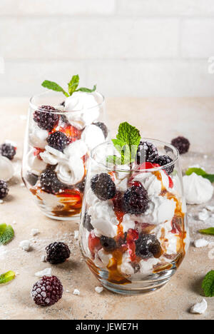 Traditionelle englische Dessert. Eton Mess - Sahne, Baiser, frische Brombeeren, Sauce und Karamell. Gläser auf einem Leuchttisch Stein zu dienen. Co Stockfoto