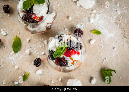 Traditionelle englische Dessert. Eton Mess - Sahne, Baiser, frische Brombeeren, Sauce und Karamell. Gläser auf einem Leuchttisch Stein zu dienen. Co Stockfoto