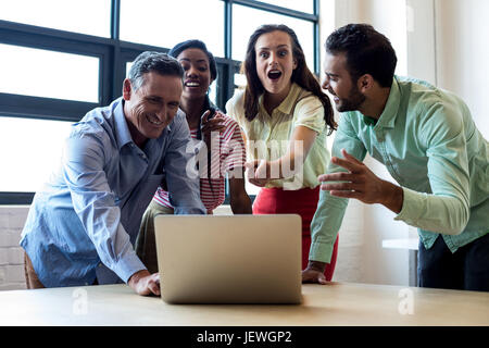 Kollegen diskutieren mit Laptop Stockfoto