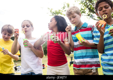 Kinder blowing Bubbles Zauberstab im park Stockfoto