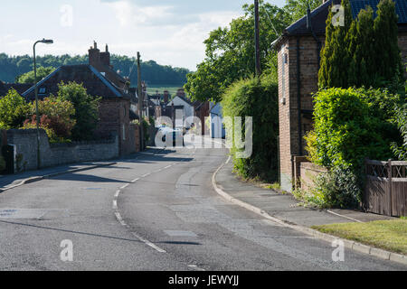 Eine gekrümmte Straße an einem sonnigen Tag im ländlichen England. Barrow Street, viel Wenlock, Shropshire, UK. Stockfoto