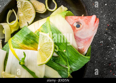 Fisch. Fisch und Meeresfrüchte. Asiatischen und osteuropäischen Küche. Roter Buntbarsch, eingehüllt in Lauch Zwiebel mit Scheiben von Kalk, Kräuter und Gewürze. Eingelegte. Bereit zum Backen, Grillen Stockfoto