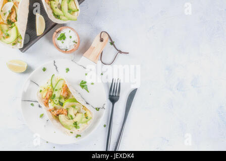 Gesunde Ernährung-Snack. Tortillas Taco mit Avocado, frische Salsa, Salat, gegrilltes Hähnchen, Kalk. Mit Joghurt & Petersilie Sauce. Auf leichten grauen Stein Marmor Stockfoto