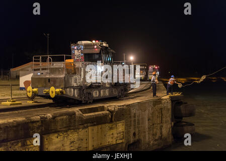 Ein Arbeiter wirft ein Seil, einem Schiff, um den Transit durch Gatun Schleuse in den Panama-Kanal in der Nacht zu unterstützen. Stockfoto