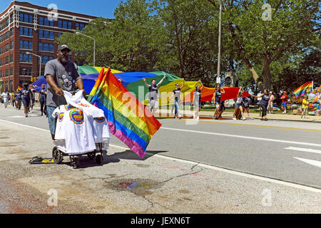 Anbieter verkaufen LGBT Pride 2017 T-shirts und Flaggen entlang der Paradestrecke in der Innenstadt von Cleveland, Ohio, während eine große Regenbogenfahne von getragen wird. Stockfoto