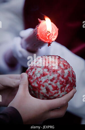 Detail reuige rot hält eine Kerze Gießen Wachs auf eine Kugel, die ein Kind in der Hand, während der Karwoche, Spanien hält Stockfoto