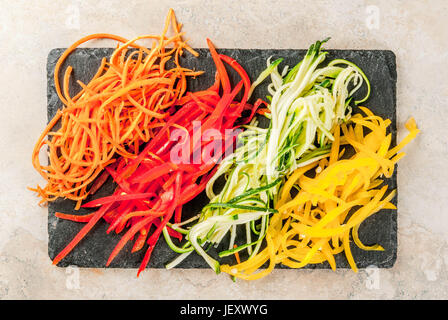 Vegane Ernährung, Diät. Gemüse-Nudeln, Teigwaren aus Karotten, Zucchini, Paprika. Auf einer Tafel Schiefer auf einem Steintisch. Draufsicht Textfreiraum Stockfoto