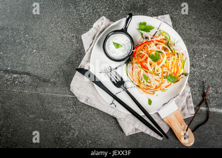 Vegane Ernährung, Diät. Einen warmen Salat, Reis Nudeln garnieren und rohe Gemüse Nudeln, Karotten einfügen, Zucchini, Paprika. Auf weiße Marmorplatte auf eine Registerkarte "Stein" Stockfoto