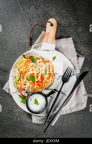 Vegane Ernährung, Diät. Einen warmen Salat, Reis Nudeln garnieren und rohe Gemüse Nudeln, Karotten einfügen, Zucchini, Paprika. Auf weiße Marmorplatte auf eine Registerkarte "Stein" Stockfoto