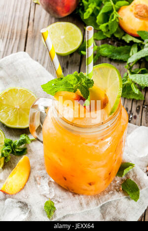 Sommer-Drinks, Cocktails. Veganes Essen. Pfirsich Smoothies, Saft oder Limonade. In ein Einmachglas mit Kalk zerkleinert Eis und Minze Blätter. Auf einem alten rustikalen woo Stockfoto