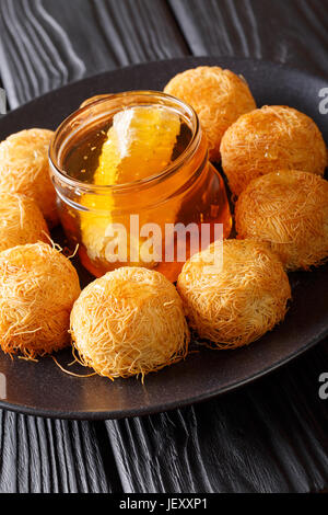 Köstliche Middle Eastern Kanafeh Gebäck mit frischem Honig Nahaufnahme auf einer Platte. Vertikal Stockfoto
