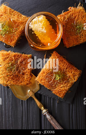 Türkisches Dessert Künefe mit Pistazien-Pulver, Kataifi Teig Nahaufnahme auf einem Tisch. vertikale Ansicht von oben Stockfoto