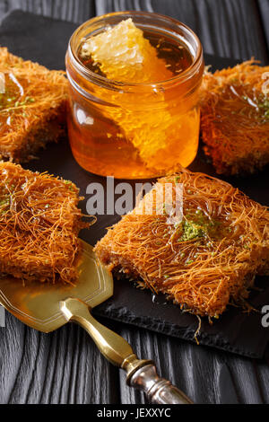 Orientalische Speisen: Kunafeh mit Pistazien und Honig-close-up auf dem Tisch. vertikale Stockfoto