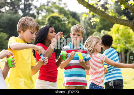 Kinder blowing Bubbles Zauberstab im park Stockfoto