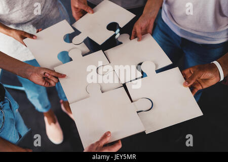Team der Jungunternehmer kombinieren Teile des Puzzles. Konzept der Integration und Partnerschaft Stockfoto