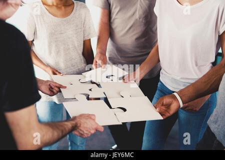 Team der Jungunternehmer kombinieren Teile des Puzzles. Konzept der Integration und Partnerschaft Stockfoto