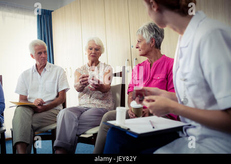 Senioren reden mit Krankenschwester über Medikamente Stockfoto