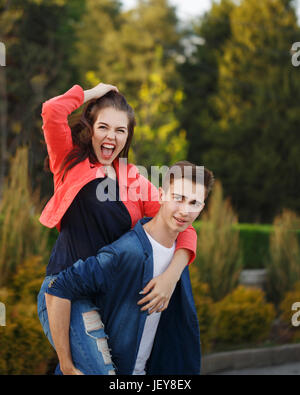 Guy rollt seine Freundin Piggyback. Verliebte Jugendliche an einem Tag. Spaß und Romantik des ersten Datums. Paar in der Liebe. Stockfoto