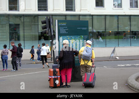 Amerikanische Touristen mit Gepäck auf den Straßen von Glasgow Blick auf Stadtplan Stadtführer Stockfoto