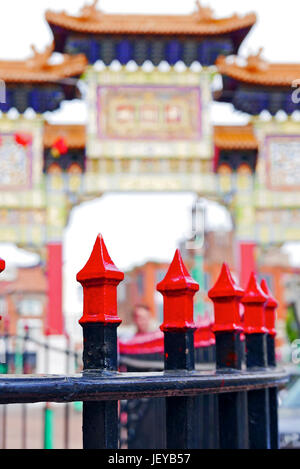 Schwarz-rot lackiertes Eisengeländer vor einem außer Fokus geratenen chinesischen Bogen in Chinatown, Liverpool, IUK Stockfoto