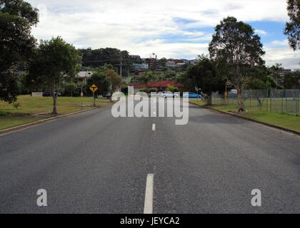 Straße in Coffs Harbour, New South Wales. In der Nähe der verlassenen Straße in Australien mit Verkehrszeichen, T-Punkt, Speed Limit-Anzeige, Bushaltestellen, Häuser, Autos. Stockfoto