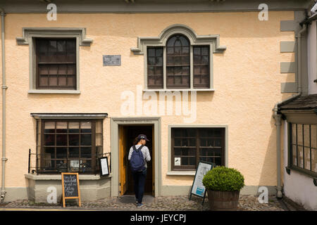 UK, Cumbria, Hawkshead, Main Streeet touristischen Beatrix Potter Galerie betreten Stockfoto