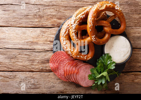 Deutsches Essen: geschnittene Wurst und Brezeln mit Sahnesoße Nahaufnahme auf dem Tisch. horizontale Ansicht von oben Stockfoto